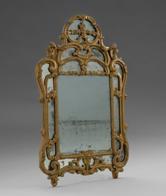 un miroir richement décoré, doté d'un cadre doré sur fond gris