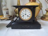 a small black clock sitting on a table next to a lamp