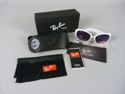 Des lunettes de soleil Ray-Ban et un chiffon de nettoyage sont posés sur une table
