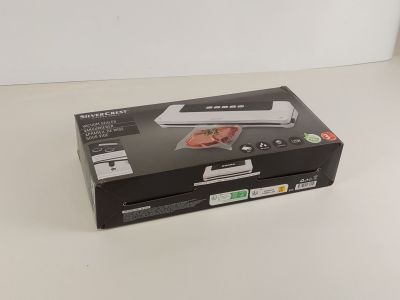 une boîte ouverte contenant un aspirateur, posée sur une table blanche