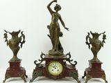 trois statues en bronze représentant une femme et deux vases posés sur une table