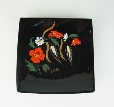 une assiette noire décorée de fleurs et d'oiseaux