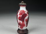 a red and white vase sitting on top of a wooden stand