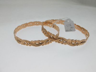 pair of gold tone bracelets on white background with price tag
