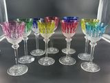Plusieurs verres à vin de différentes couleurs sont alignés sur une table