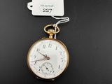 une vieille montre de poche à laquelle est attachée une étiquette, posée sur une surface noire
