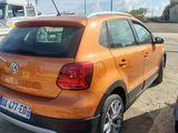 an orange car parked next to a boat in a parking lot