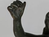 bronze statue of a boy holding a tennis racquet in one hand and a tennis ball in the other