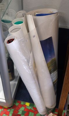 many rolls of white paper on the floor next to a refrigerator