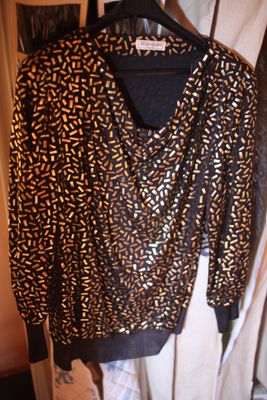 un pull marron et noir avec un imprimé animalier, suspendu à un cintre