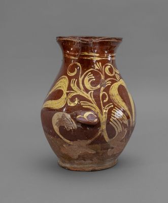 brown and gold vase with a bird on it on a gray surface
