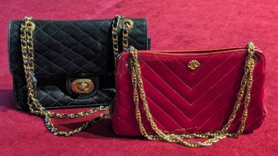 two black and red purses with gold chains on a red surface