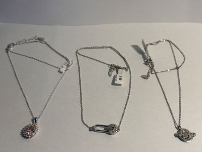 three necklaces with charms and charms on a white surface