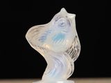 une sculpture en verre représentant un oiseau, posée sur une table