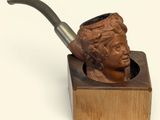 une statue représentant un homme tenant une pipe dans un support en bois
