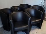 Plusieurs fauteuils en cuir noir sont alignés dans une salle d'attente