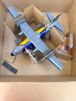 un petit avion en carton posé sur une table, dans une boîte en carton