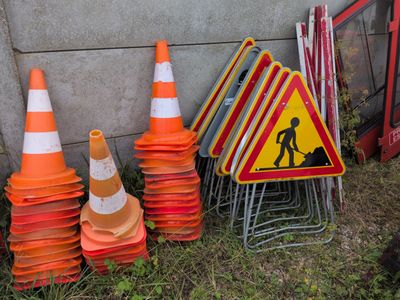 une pile de cônes de signalisation et un panneau de chantier près d'un mur