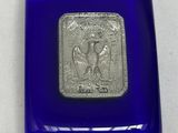 une image représentant une boîte en verre bleu ornée d'un sceau argenté