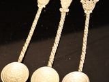four silver spoons sitting on top of a table next to each other