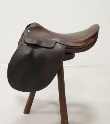 an image of a saddle on a wooden stand against a white wall