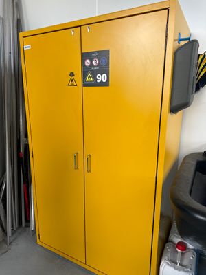 une armoire jaune dans un garage, à côté d'une poubelle noire