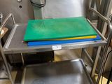 une table en métal sur laquelle est posée une planche à découper verte