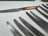 several knives are lined up on a table with a knife in front of them
