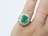an image of a woman ' s hand holding a ring with an emerald stone