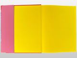 a close up of a yellow and pink book open on a white surface