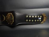 black and gold leather belt with gold studded buckle on a black surface