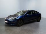 une Tesla Model 3 bleue garée dans une pièce blanche