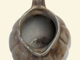 a brown vase with a hole in it on a white surface