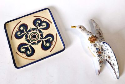 une petite assiette sur laquelle est représenté un oiseau, à côté d'une autre petite assiette sur laquelle est représenté un oiseau