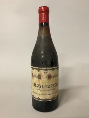 une vieille bouteille de vin posée sur une table blanche