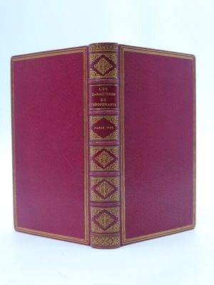 un vieux livre à la couverture rouge posé sur une table blanche