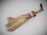 a close up of a tassel on a white surface with a small figure in the background