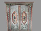 a wooden cabinet with two doors and a flower design on the door