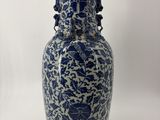 un vase bleu et blanc posé sur une surface blanche