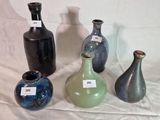 quatre vases différents posés sur une table, sur lesquels sont apposées des étiquettes