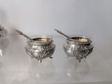 two silver bowls with spoons sitting on a glass table