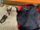deux pulls dans une boîte, avec une étiquette de prix dessus