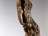 bronze statue of a woman holding a bird on a pedestal