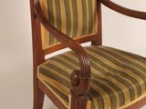 an antique wooden chair with striped upholstered seat and arms
