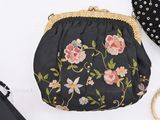 a black purse with pink flowers on it next to a black purse