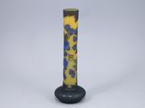 un vase jaune et bleu orné de fleurs bleues, posé sur une surface blanche