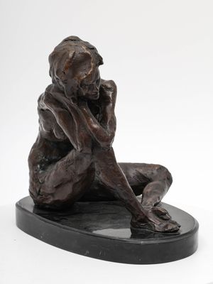statue en bronze représentant une femme assise sur un socle noir, les mains sur le visage