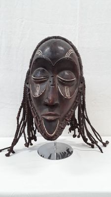 a close up of a wooden mask on a stand on a table
