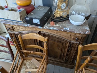 plusieurs chaises et une table sur laquelle est posée une horloge, dans une pièce