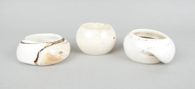 trois vases blancs posés les uns à côté des autres sur une table